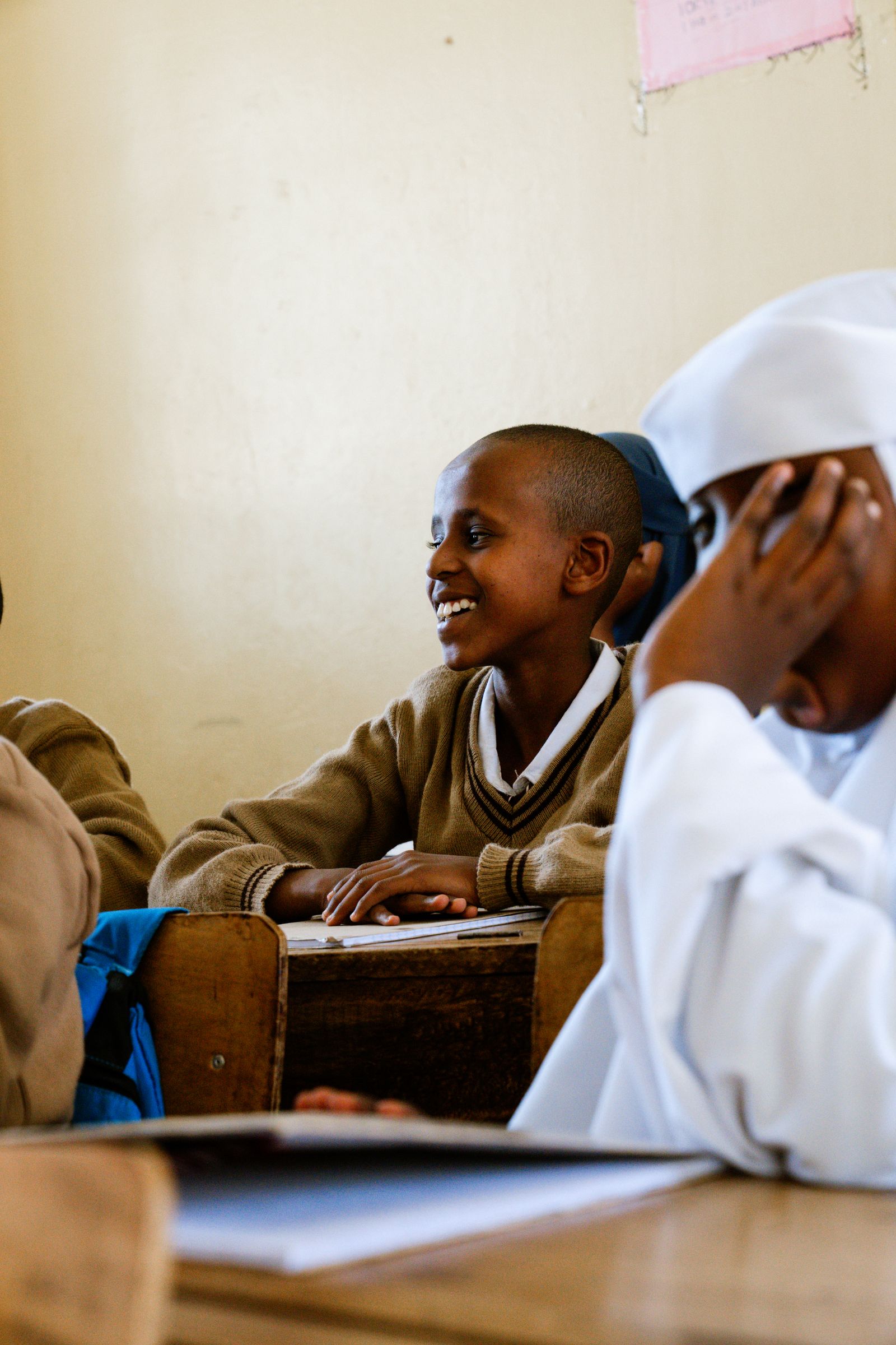 A student smiling at her desk in a classroom